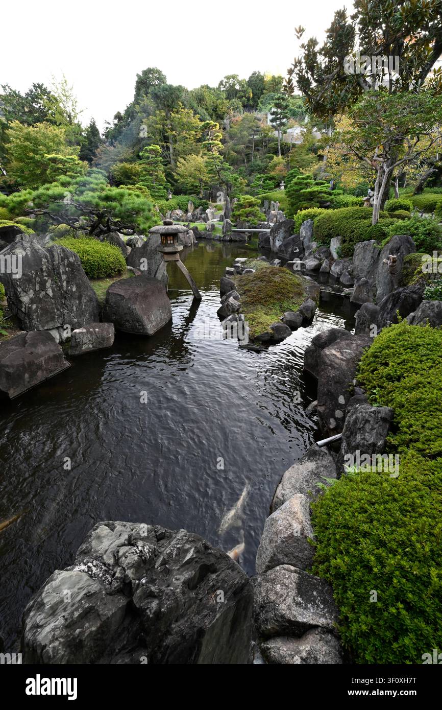 Ein ruhiger Teich, umgeben von gepflegten Kiefern, monumentalen Steinen und sorgfältig geschnittenen Sträuchern im Hanbe-Garten, dem historischen Kaiseki-Restaurant in Hiros Stockfoto