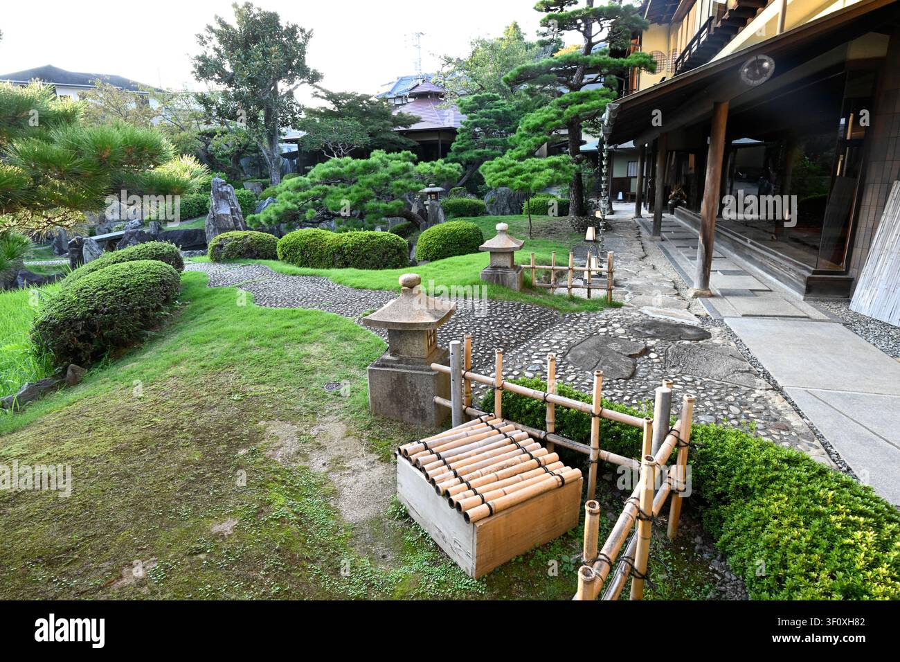 Traditionelle Steinlaternen, Kieselstege und kunstvoll geschnittene Kiefern umrahmen die eleganten Gärten des Hanbe Garden, einem historischen Kaiseki-Restaurants in Hiroshima, Stockfoto