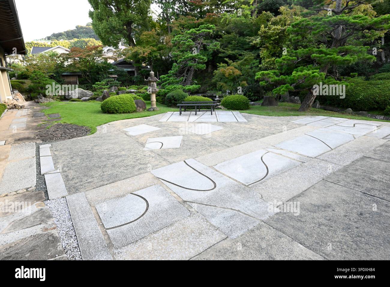 Zeitgenössischer steinpflasterter Innenhof im Hanbe-Garten, dem historischen Kaiseki-Restaurant in Hiroshima, Japan. Geometrische Granitpflasterung verschmilzt mit gestalteten Stockfoto