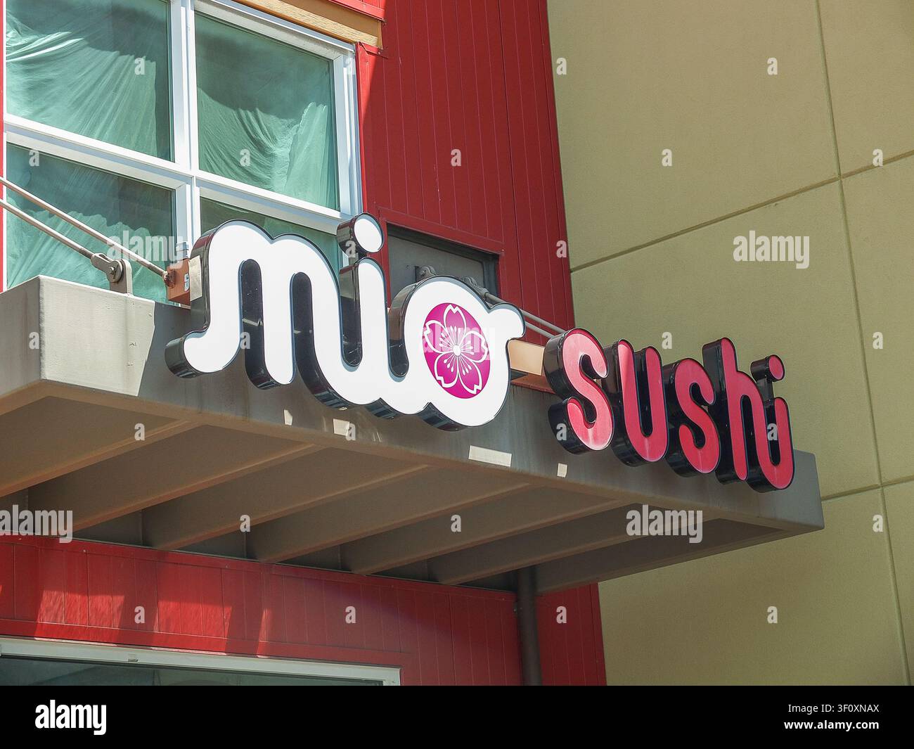 Neon-Schild des Mio Sushi-Restaurants an einer modernen rot-beigen Gebäudefassade in Ruston. - 13. Juni 2026 Ruston WA, USA Stockfoto