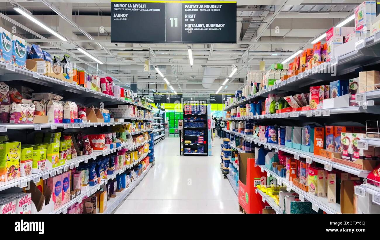 Supermarkt-Lebensmittelgang mit voll bestückten Regalen mit verpackten Cerealien, Nudeln und überhängenden Schildern Stockfoto