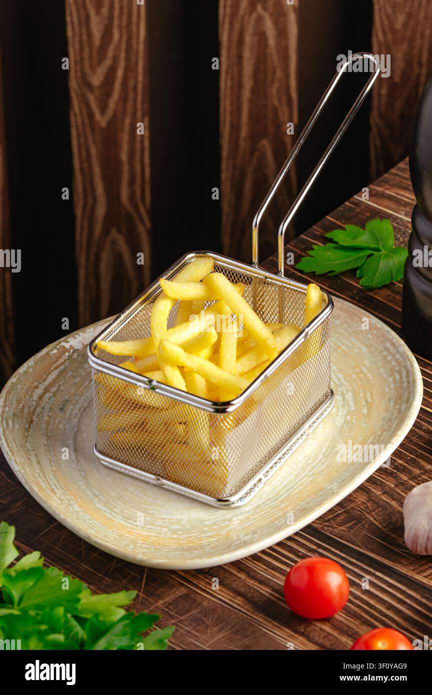 Goldene Pommes frites in einem Mini-Fritteusen-Servierkorb Stockfoto