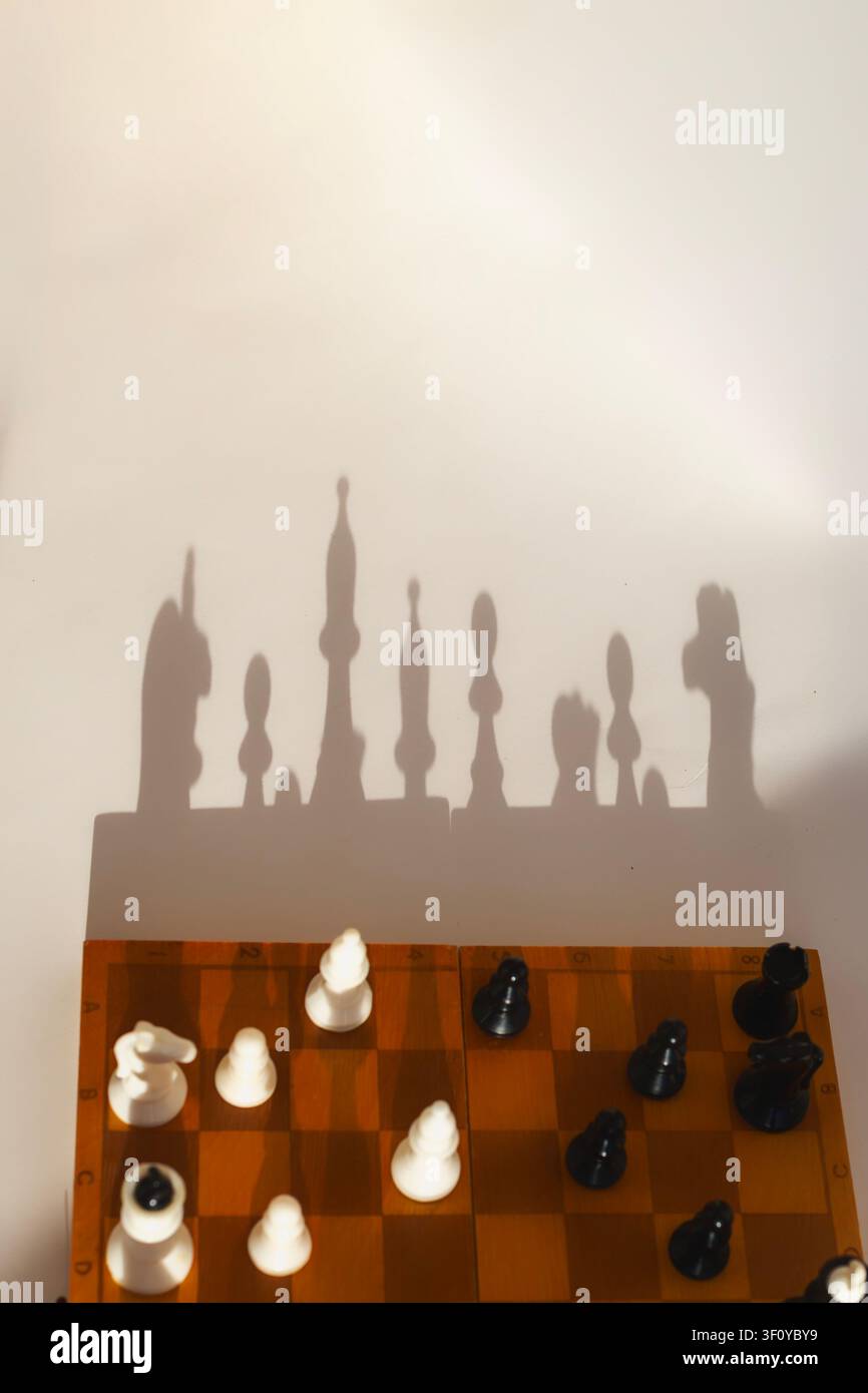 Eine vertikale Flat-Lay- und Top-Down-Aufnahme eines Holzschachbretts mit schwarzen und weißen Figuren, die zum Spielen angeordnet sind. Stockfoto