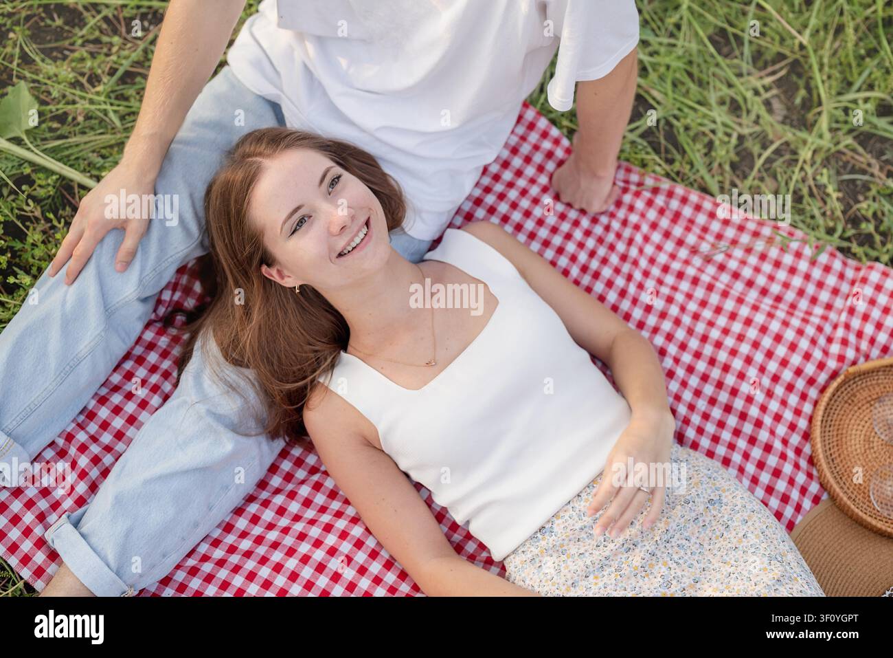 Herbstnatur. Spaß und Freizeit. Junges Teenager-Paar in weißen T-Shirts, das auf einem Sonnenblumenfeld bei Sonnenuntergang picknickt und die Zeit zusammen genießt Stockfoto