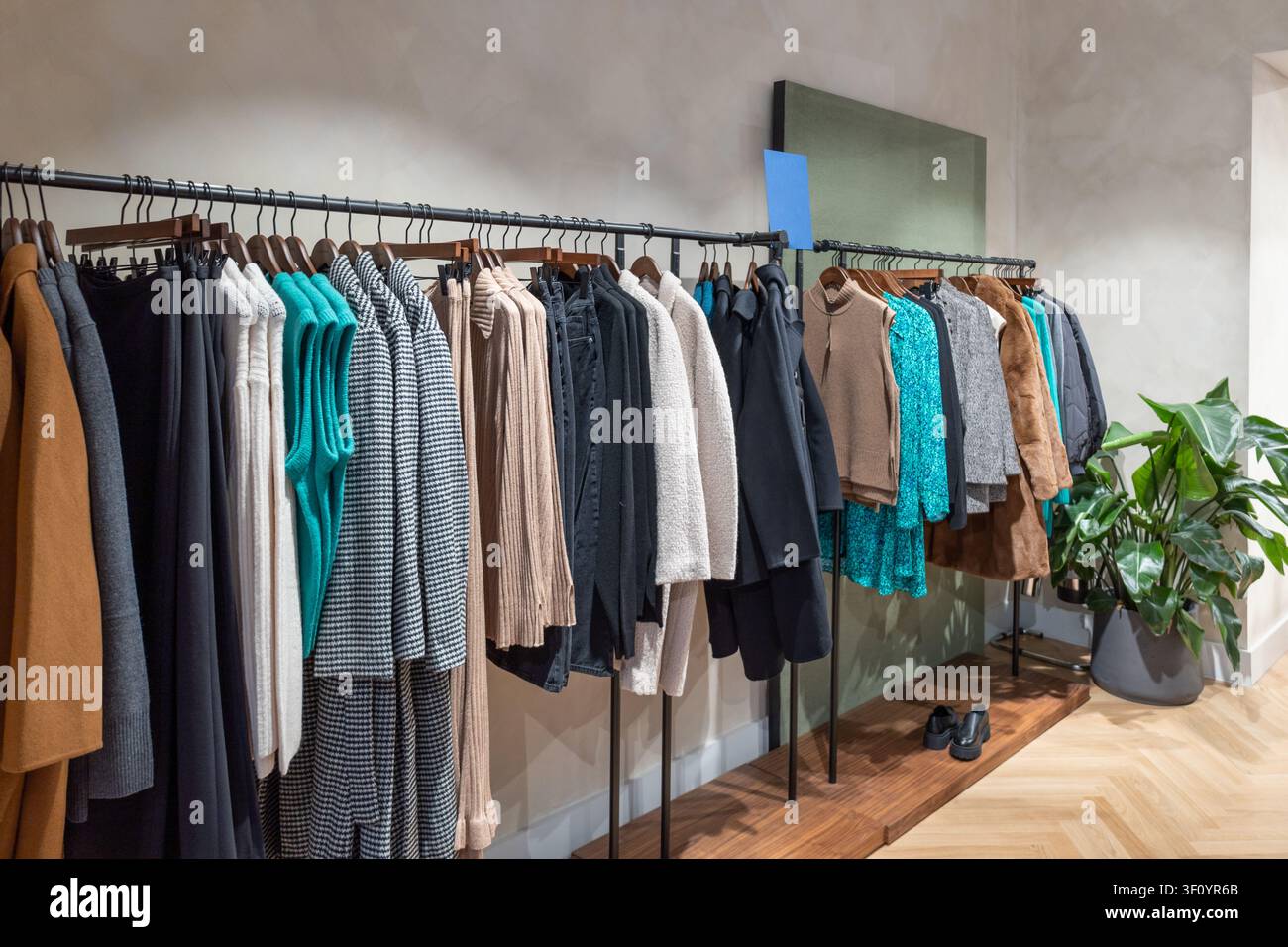Boutique-Interieur mit hängenden Kleidungsstücken und einem dekorativen Wandregal Stockfoto