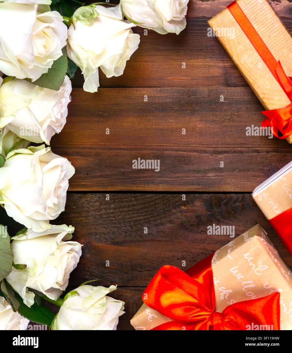 viele weiße Rosen auf einem dunklen Holzgrund mit einem Geschenk und einer roten Schleife, eine sanfte Tagespostkarte, ein Valentinstag oder ein Frauentag. Grußkarte. Ort Stockfoto