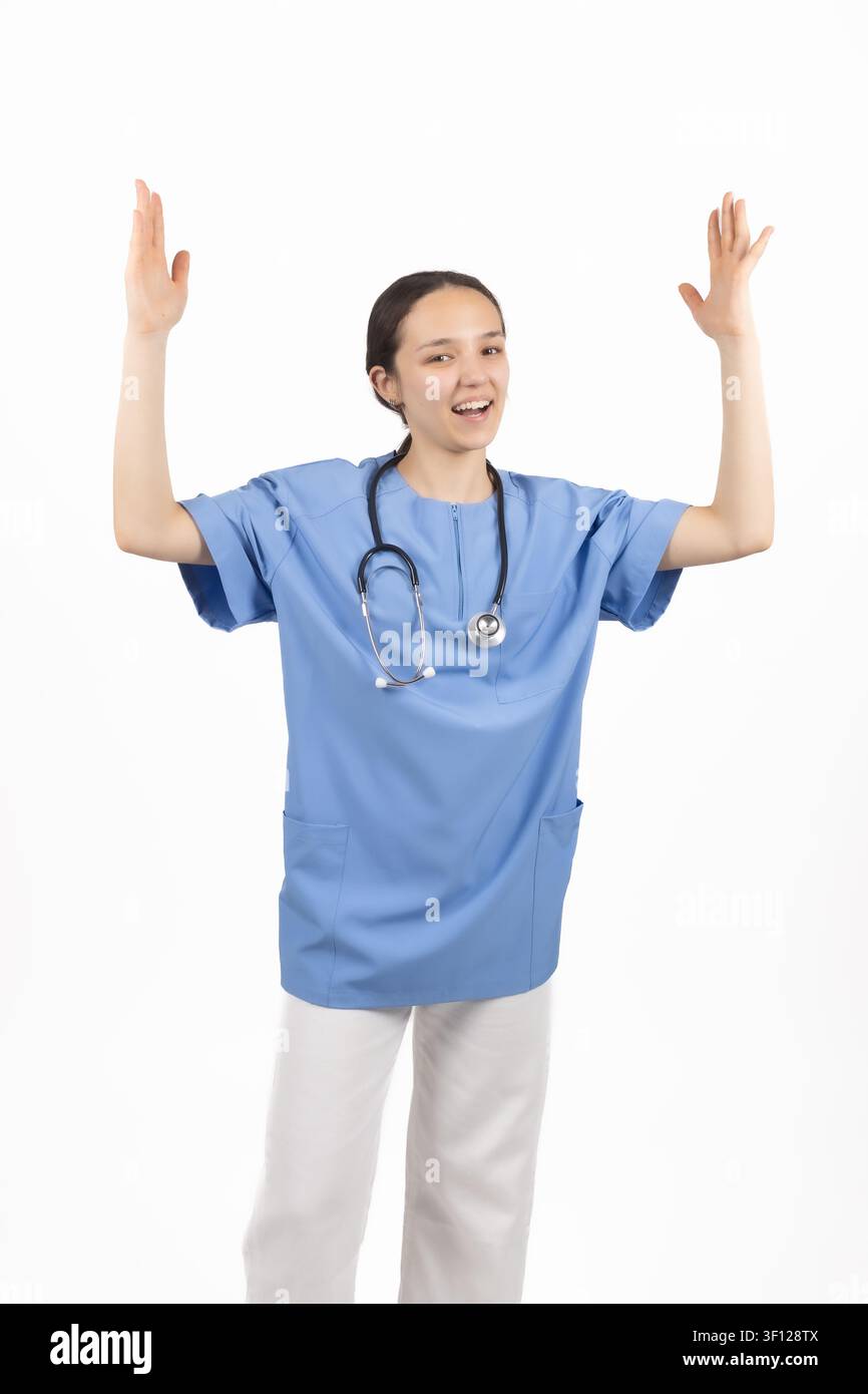 Fröhliche Ärztin in blauen OP-Kleidung, die die Arme hebt und Erfolg feiert Stockfoto