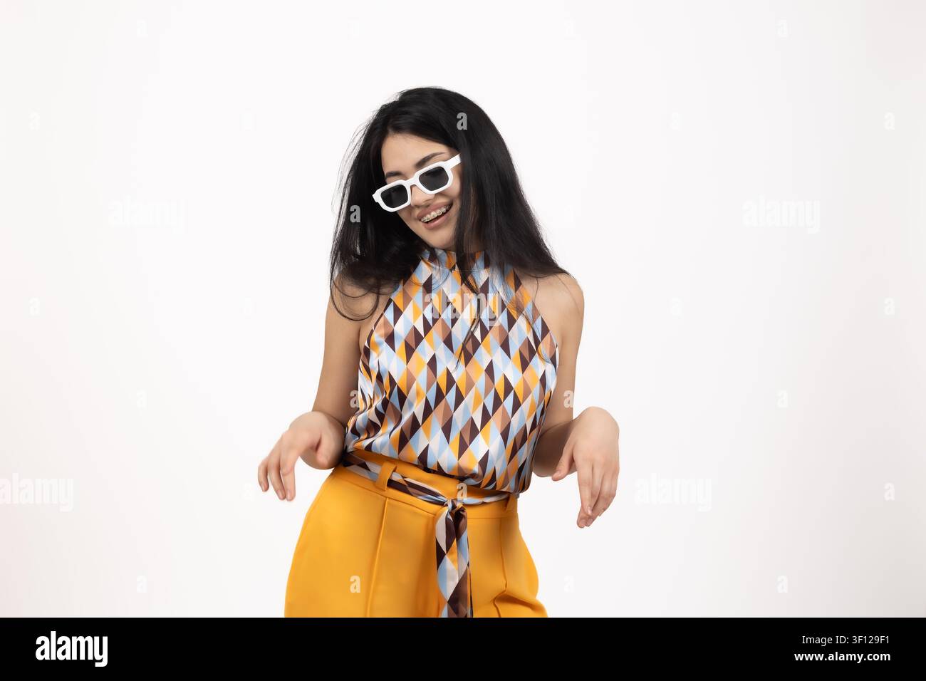 Fröhliche junge Frau mit Sonnenbrille, die posiert und in guter Stimmung tanzt Stockfoto