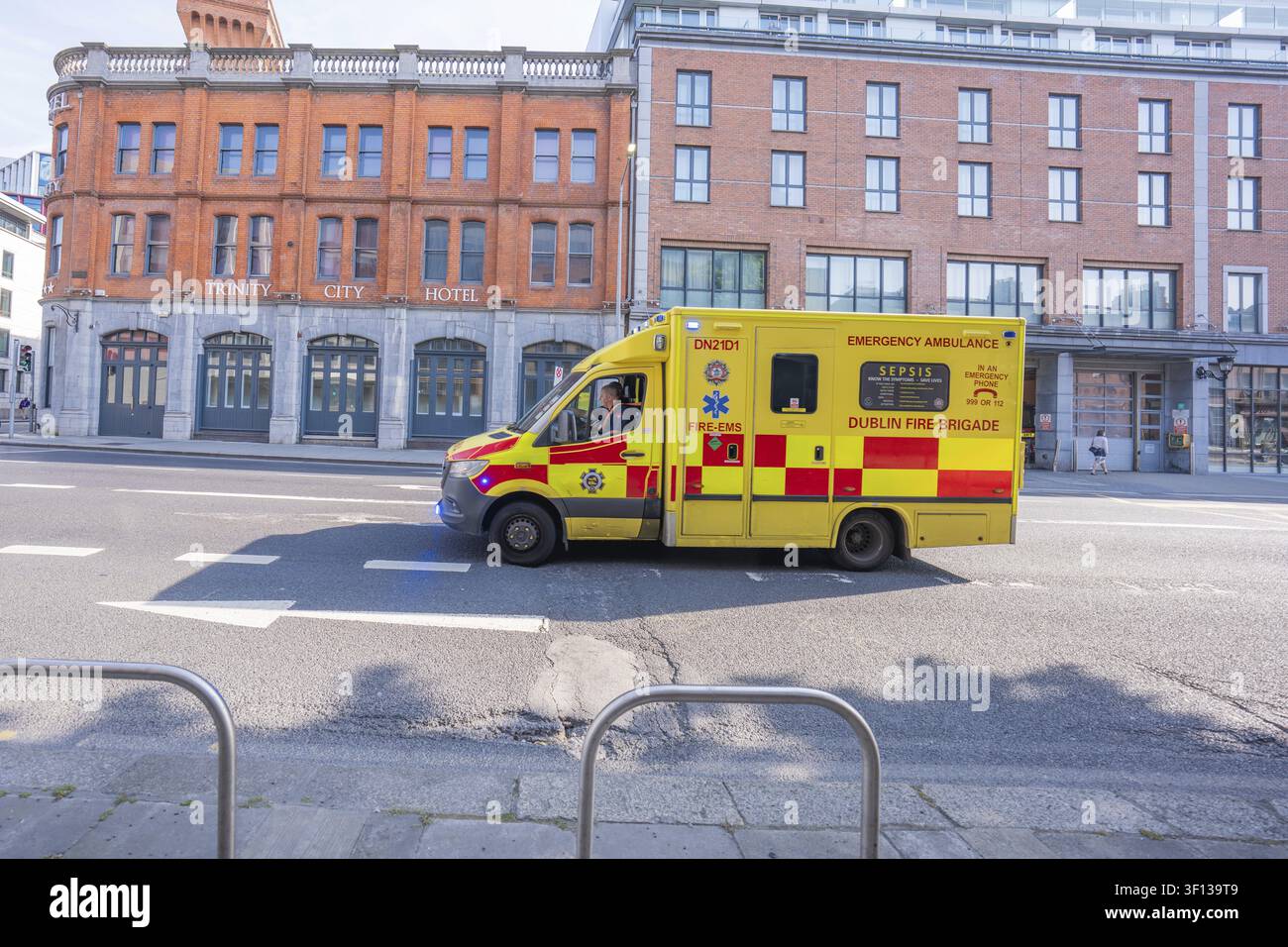 Ein gelber Rettungswagen fährt an einem roten Backsteingebäude in der Stadt Dublin, Irland, vorbei Stockfoto