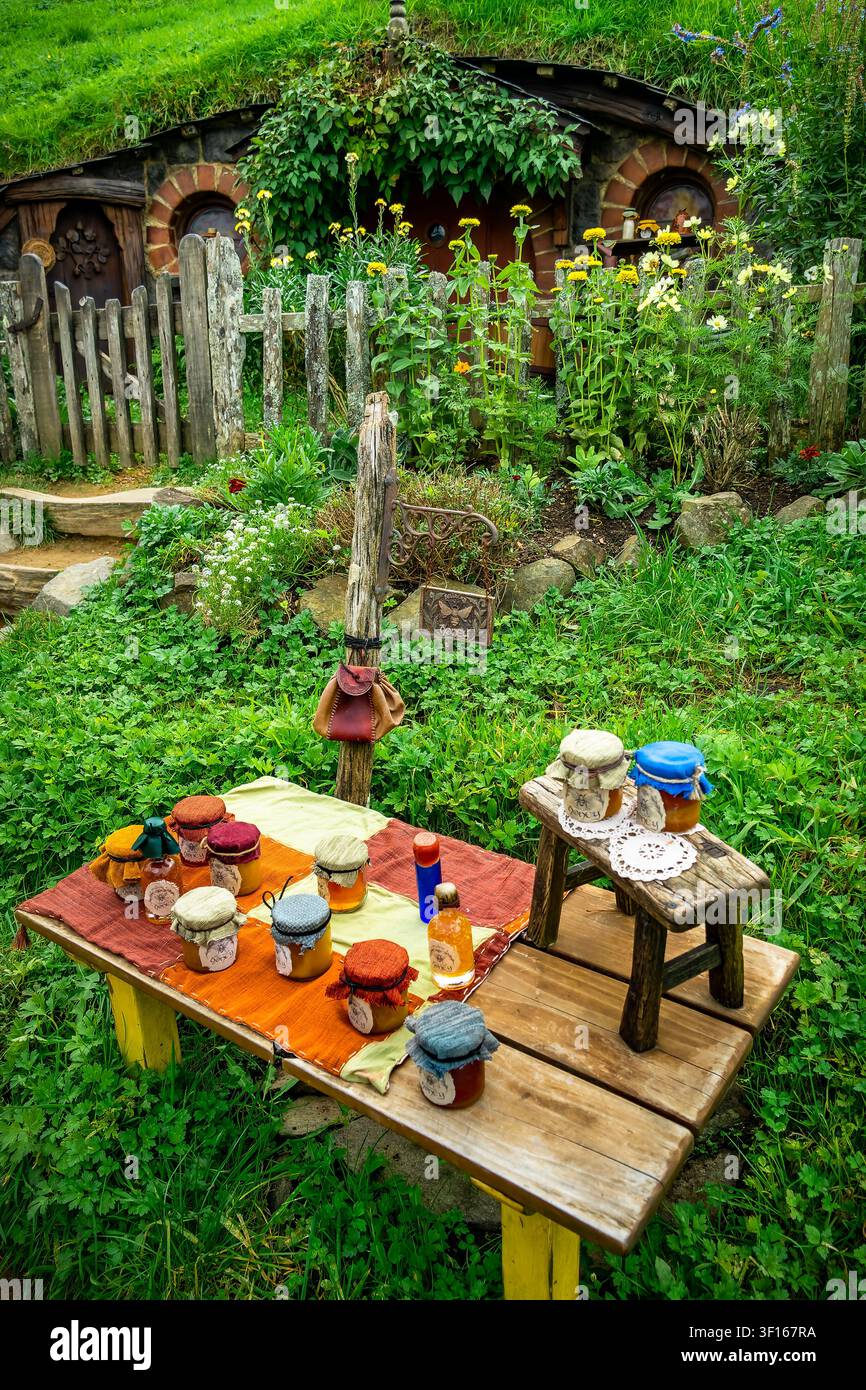 Rustikale Darstellung von kunsthandwerklichen Honiggläsern und kleinen Flaschen auf einer Holzbank am Filmset von Hobbiton in Neuseeland. Stockfoto
