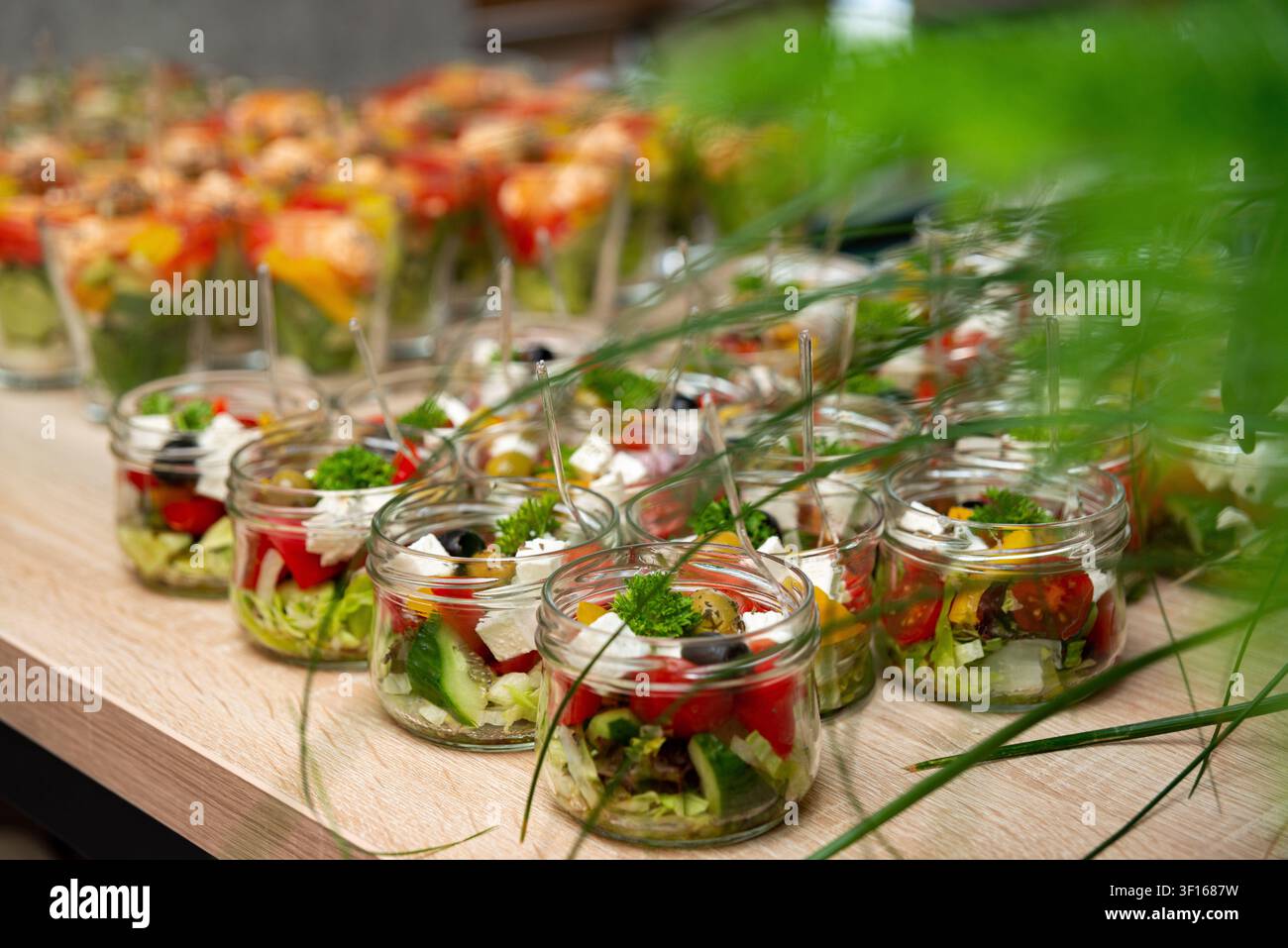 Vielzahl von frischen, farbenfrohen Salaten und Vorspeisen, die in Glasschalen auf dem Buffet-Tisch für Eventcatering und Party serviert werden. Stockfoto