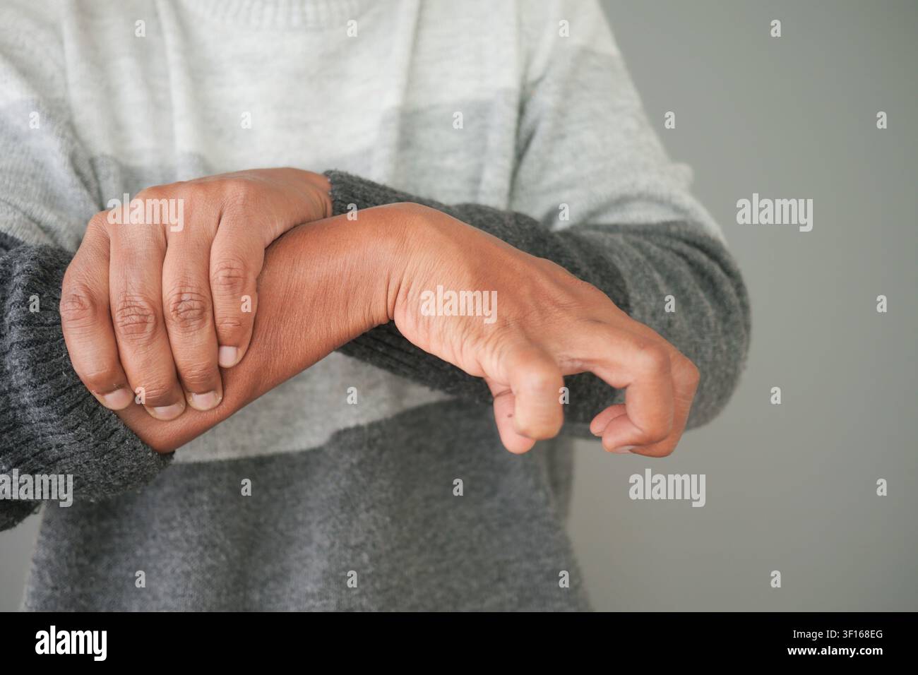 Person reibt sich das Handgelenk in einer Schmerzgebärde, die Handgelenkschmerzen, Gelenkschmerzen, Arthritis oder Juckreizlinderung anzeigt Stockfoto