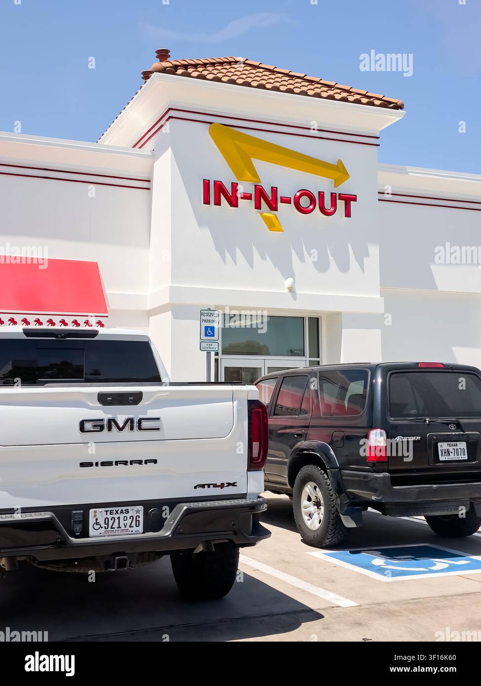 DALLAS, TX, USA - 10. JULI 2026: Außenansicht des In-N-Out Burger-Restaurants mit sichtbarer Markenbezeichnung und geparkten Fahrzeugen. GMC Sierra und Toyota 4Runner sind geparkt Stockfoto