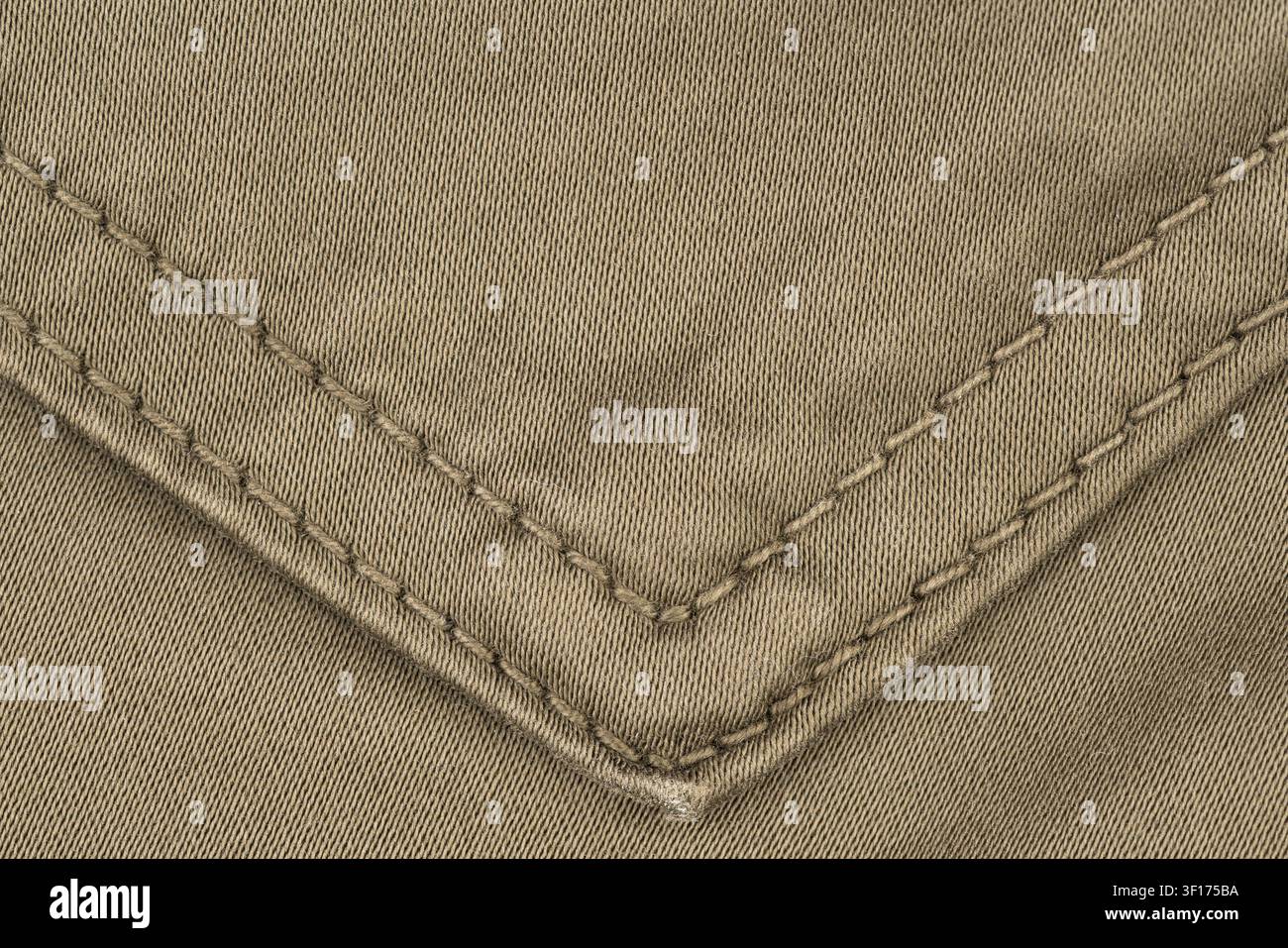 Strukturiertes olivgrünes Gewebe mit präzisen diagonalen Nähten, die eine V-Form bilden. Sanfte Beleuchtung hebt das Gewebemuster und die FadenDetails hervor Stockfoto