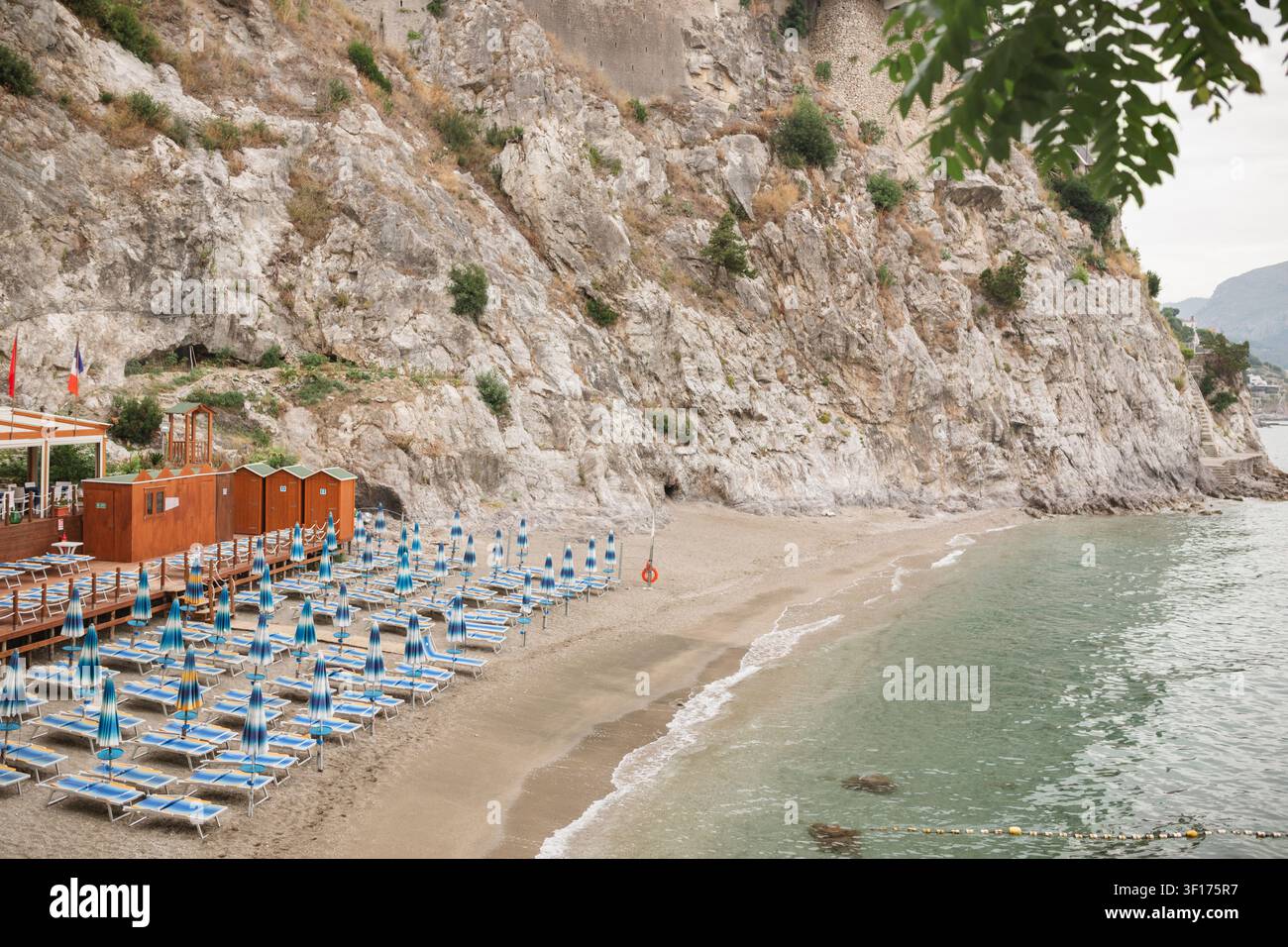 Leere Sonnenliegen und Sonnenschirme am Strand Spiaggia del Lannio bei Sonnenaufgang, Cetara, Salerno, Italien Stockfoto