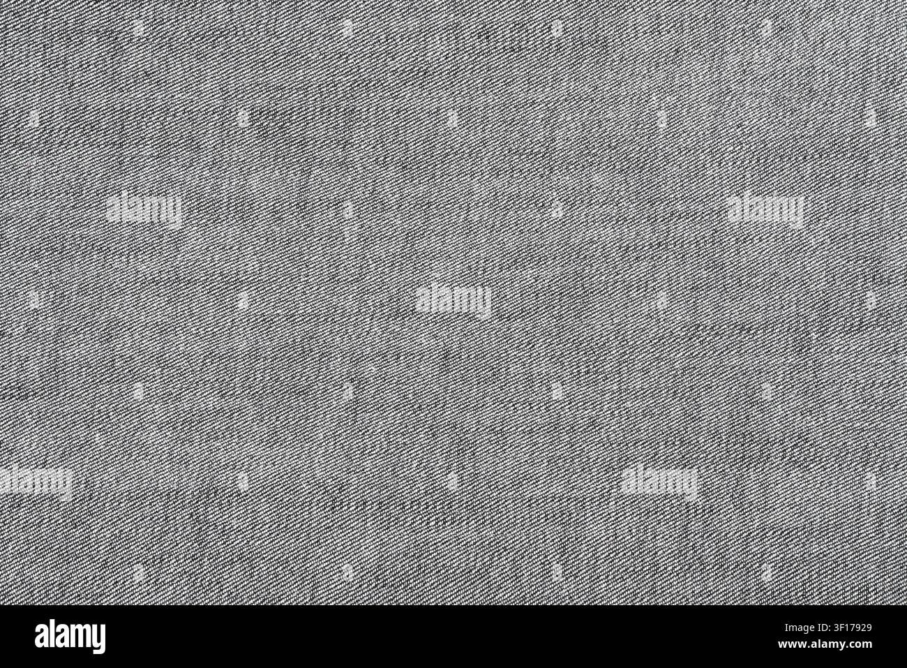 Nahaufnahme von grauem Denimstoff, der die detaillierte diagonale Webstruktur zeigt. Neutrale Töne mit subtilen Variationsmöglichkeiten in der Schattierung. Ideal für Hintergrund, Design, Te Stockfoto