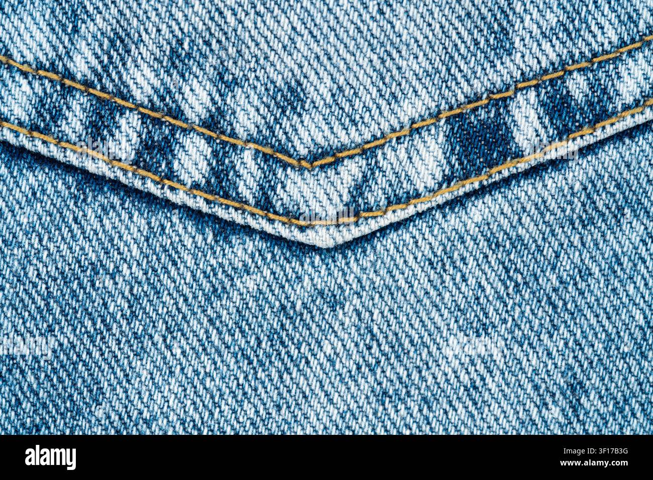 Blauer Denimstoff mit Gesäßtasche und gelben Nähten. Nahaufnahme der klassischen Jeansstruktur. Textilhintergrund für Modedesign, Bekleidungsindustrie Stockfoto