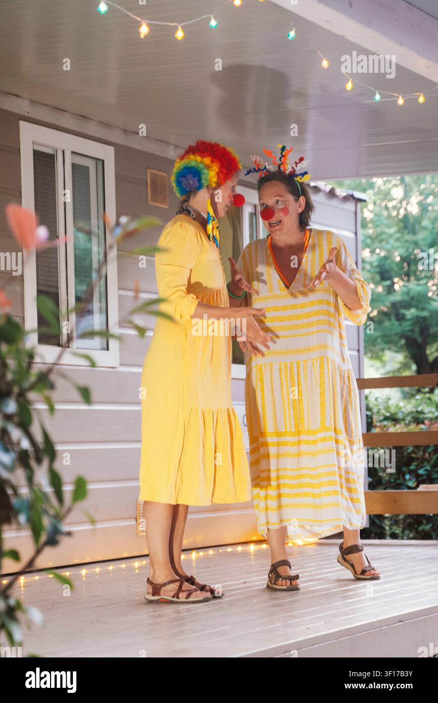 Clowns in gelben Kleidern, die auf einer Veranda auftreten Stockfoto
