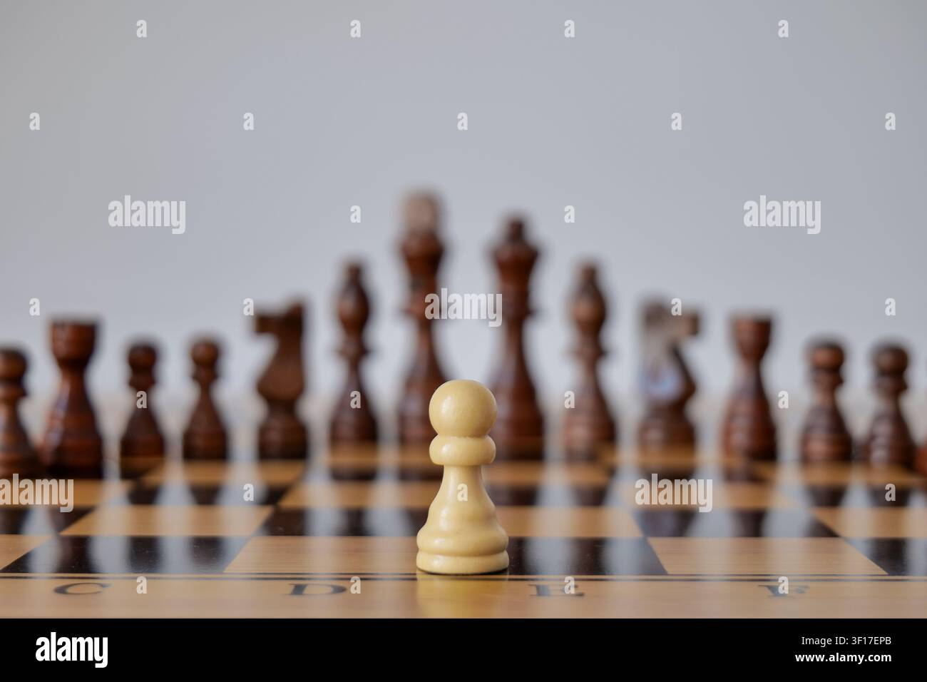 Weißer Schachbauer steht schwarzen Figuren gegenüber Stockfoto