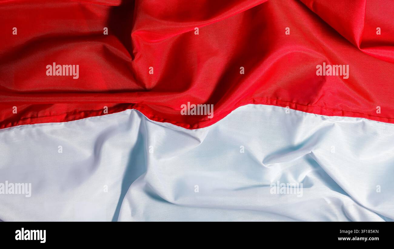 Eine Nahaufnahme-Hintergrundtextur eines welligen rot-weißen Tuches, das die Nationalflagge Indonesiens darstellt. Hochwertiges Foto Stockfoto