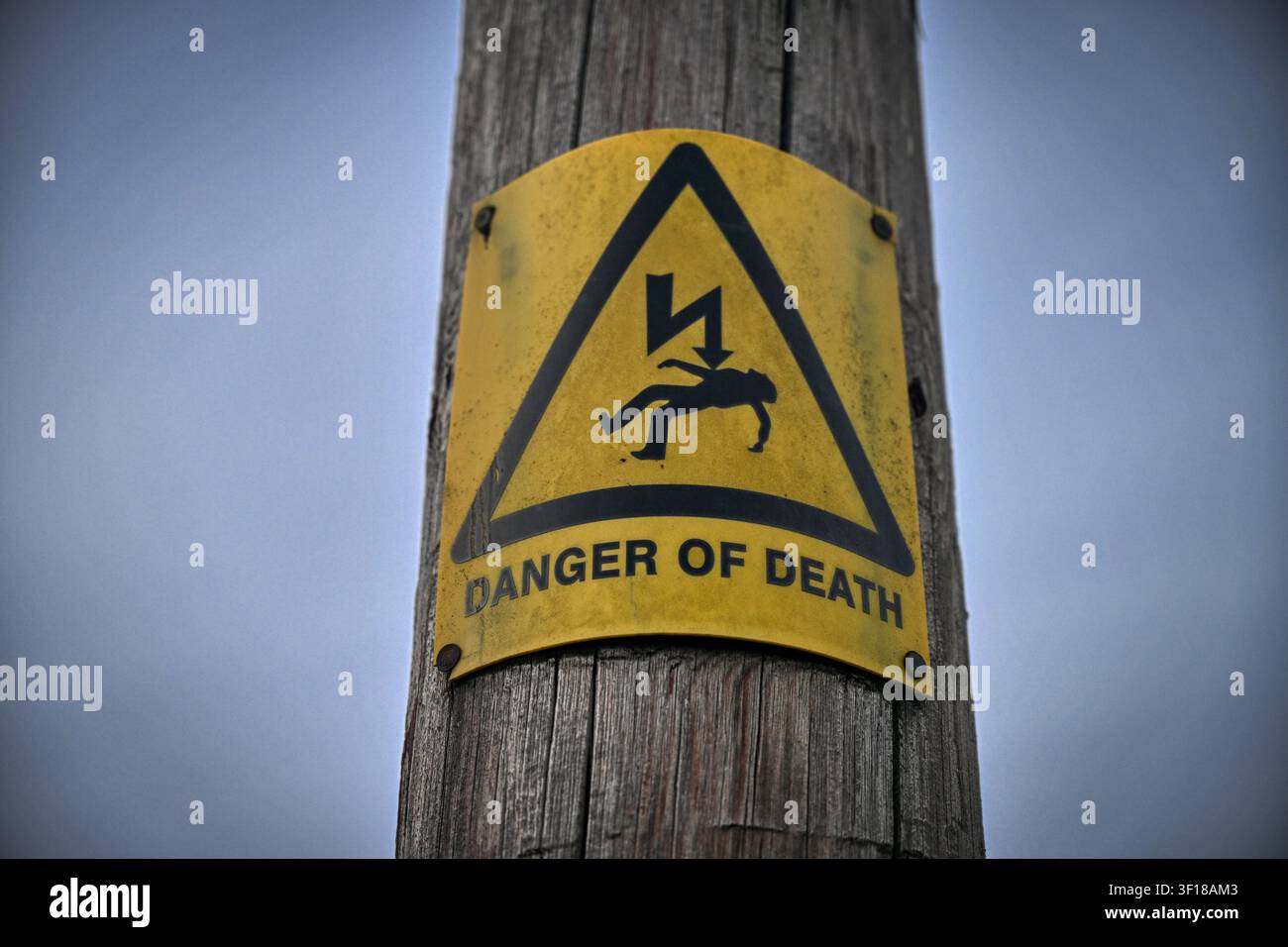 Warnschild vor dem Tod an einem hölzernen britischen Strommast Stockfoto