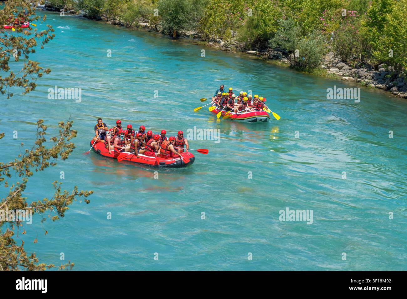 Antalya, Türkei - 03. Juni 2026: Zwei rote aufblasbare Schlauchboote befahren den Koprucay-Fluss, auf denen Gruppen von Personen mit Helmen und Schwimmwesten unterwegs sind, umgeben Stockfoto