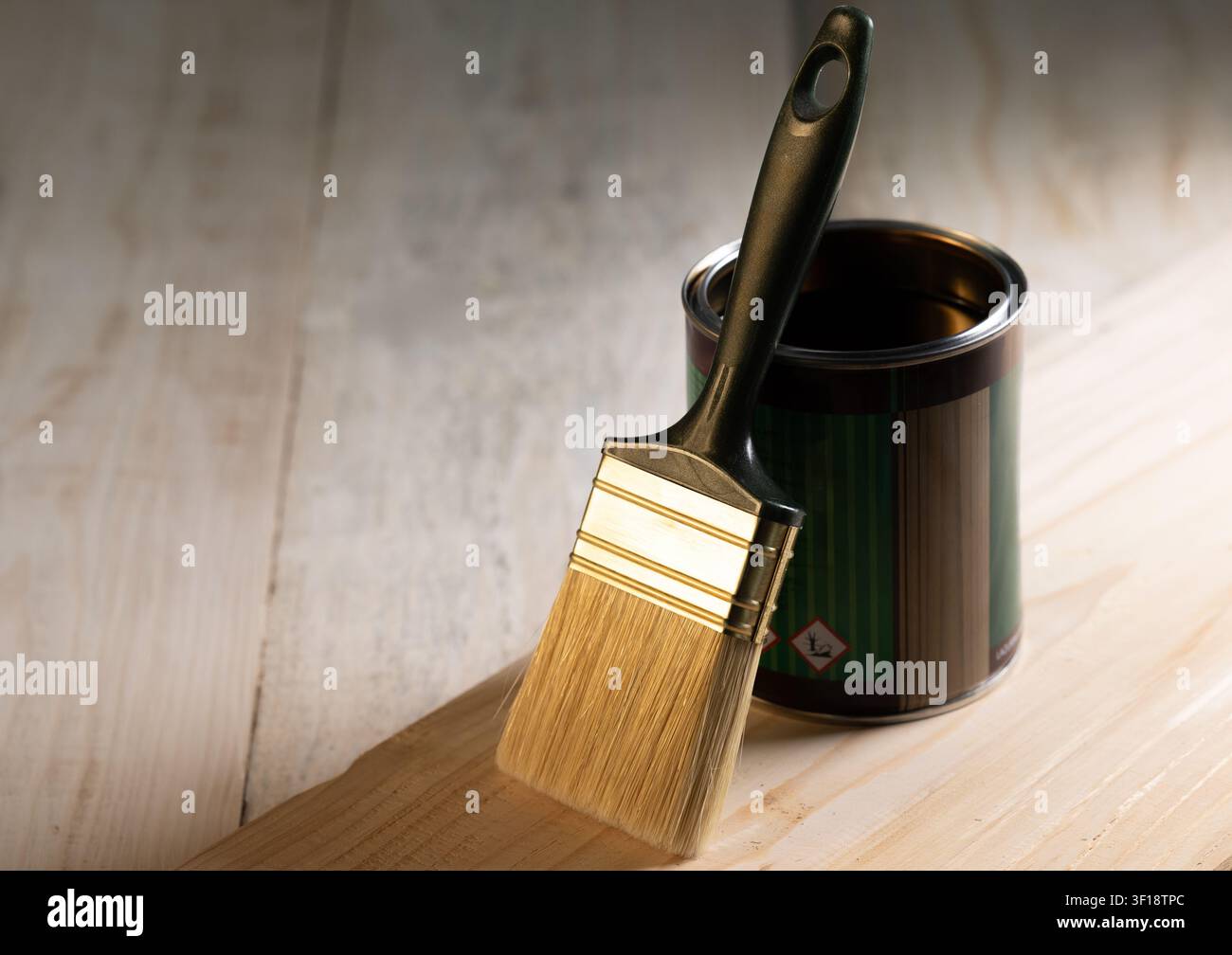 Nahaufnahme eines Pinselstrichs, der auf einer offenen Dose Holzlasur ruht, während ein Schutzlack auf eine natürliche Holzoberfläche aufgetragen wird. Konzept von DIY-Holzwo Stockfoto