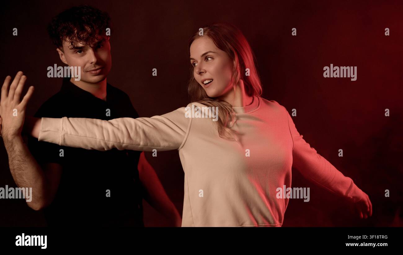 Mann, der die Hand ausstreckt und eine Frau blockiert, die sich im dramatischen roten Studiolicht entfernt Stockfoto