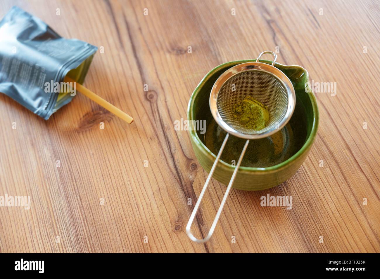 Matcha-Pulver in eine Schüssel sieben für ein selbstgemachtes Eislatterezept Stockfoto