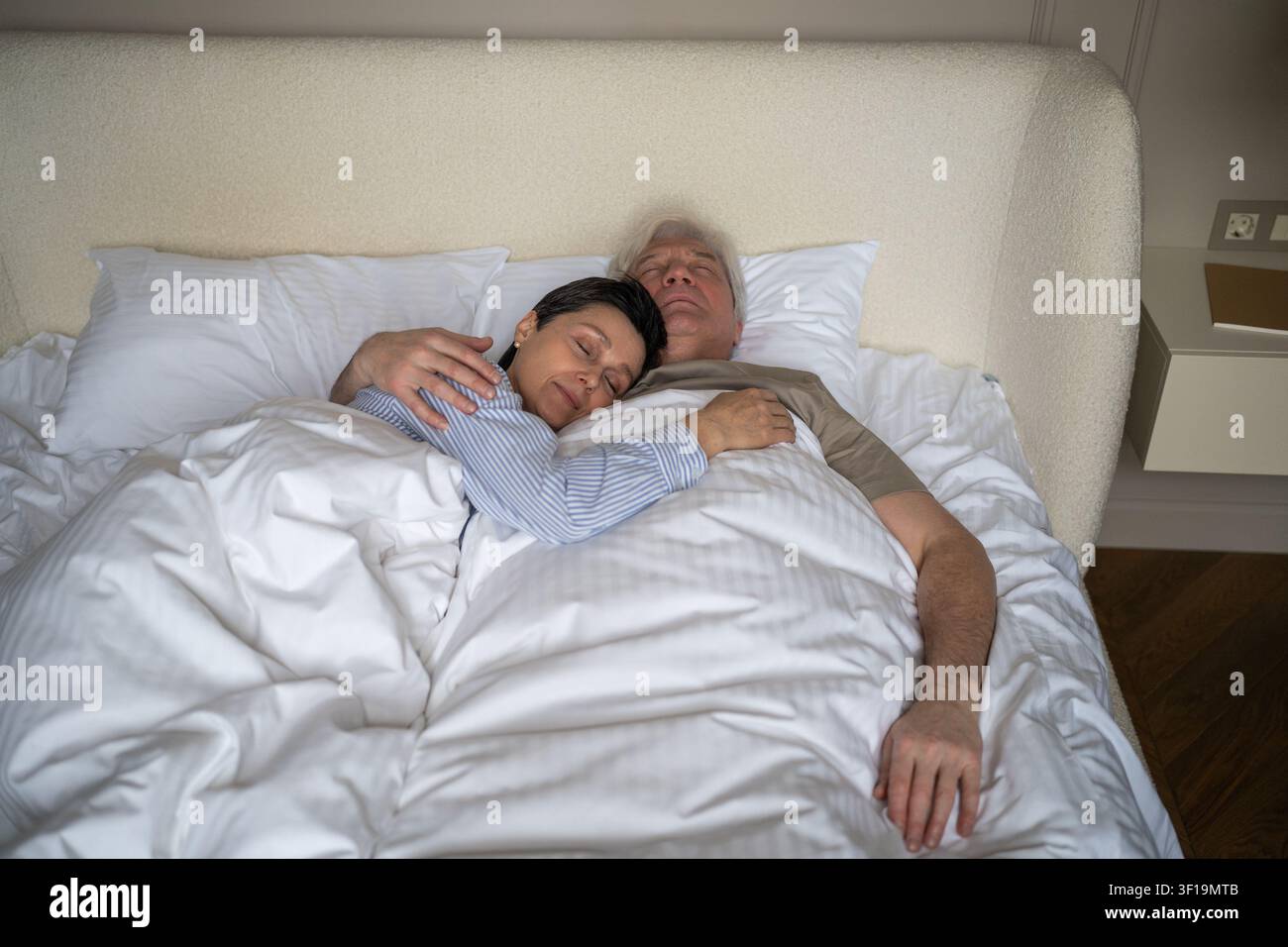 Glückliches, entspanntes, älteres Ehepaar, Ehefrau und Ehemann, schlafen ruhig im Bett und umarmen sich. Stockfoto