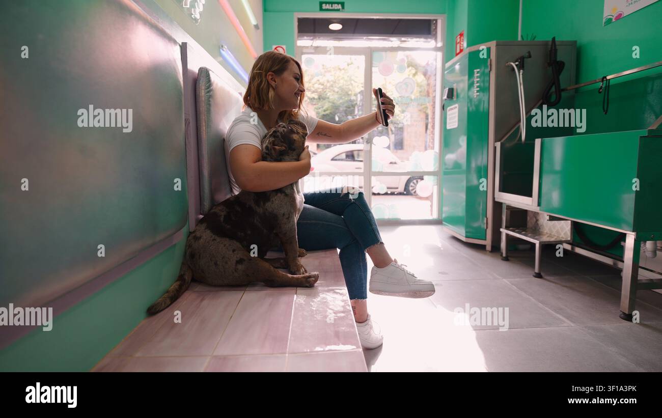 Frau und Hund teilen ein fröhliches Selfie in einer Selbstbedienungspetwäsche Stockfoto