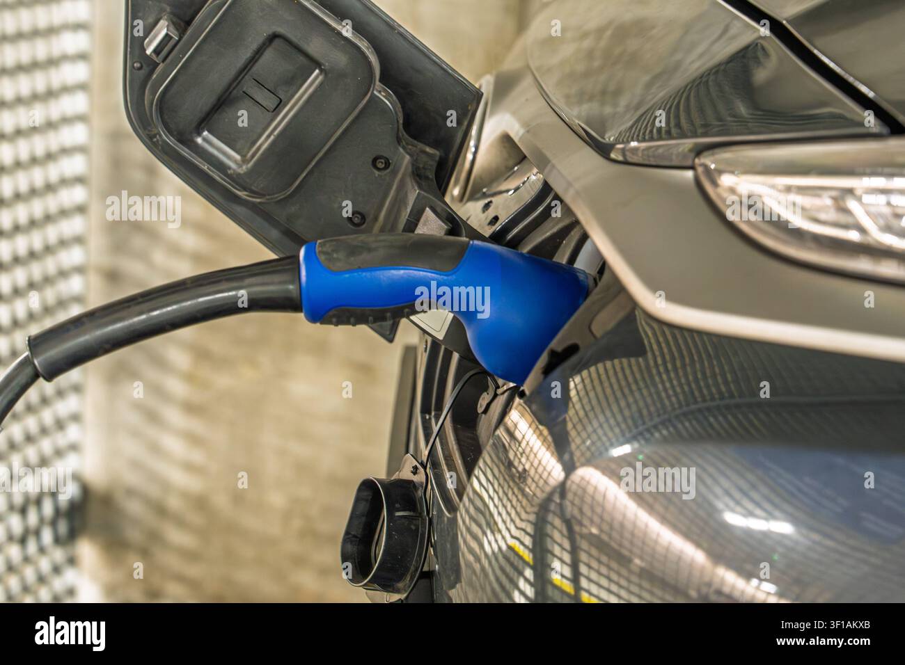 Elektrofahrzeug-Ladekabel, das in einen modernen Autoständer in den Niederlanden eingesteckt ist, Nahaufnahme Stockfoto