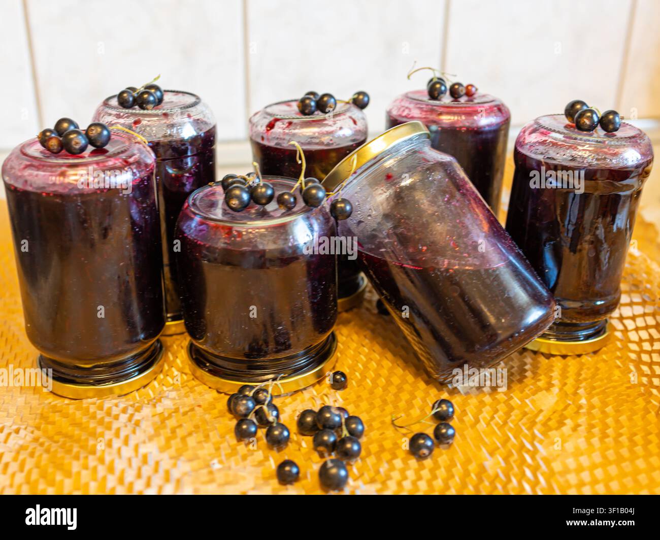Frisch zubereitete hausgemachte Schwarze Johannisbeer-Marmelade in Gläsern, verziert mit reifen Beeren, traditionelle Fruchtkonserve auf Holzunterlage Stockfoto