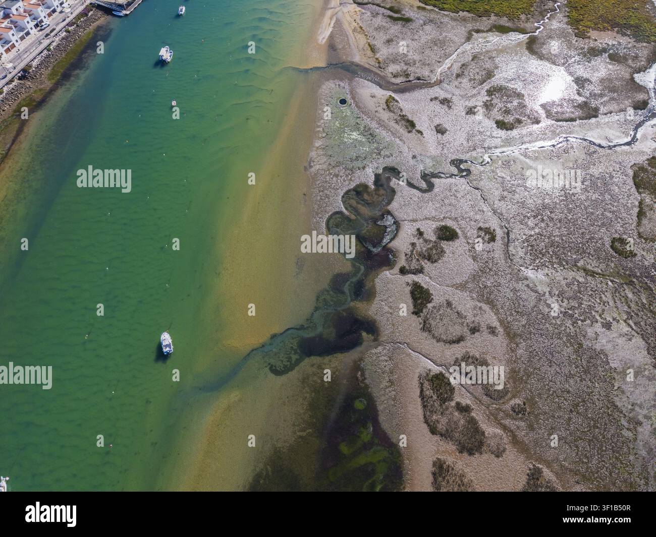 Luftaufnahme des Küstenkanals und der Sandbänke von Cabanas mit kleinen Booten, die im türkisfarbenen Wasser vor Anker liegen, und der Marschlandschaft in Cabanas, Faro, P Stockfoto