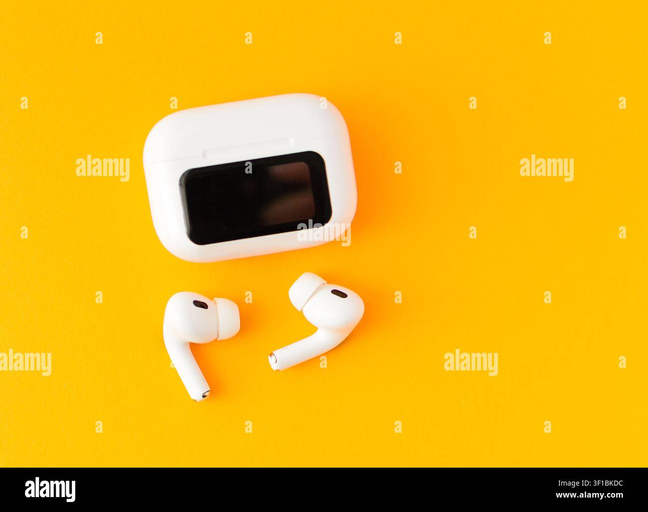 Weiße kabellose Ohrhörer mit einer Ladebox auf einem gelben Hintergrund. Minimales Technologiekonzept für Musik, Kommunikation und modernen mobilen Lebensstil Stockfoto