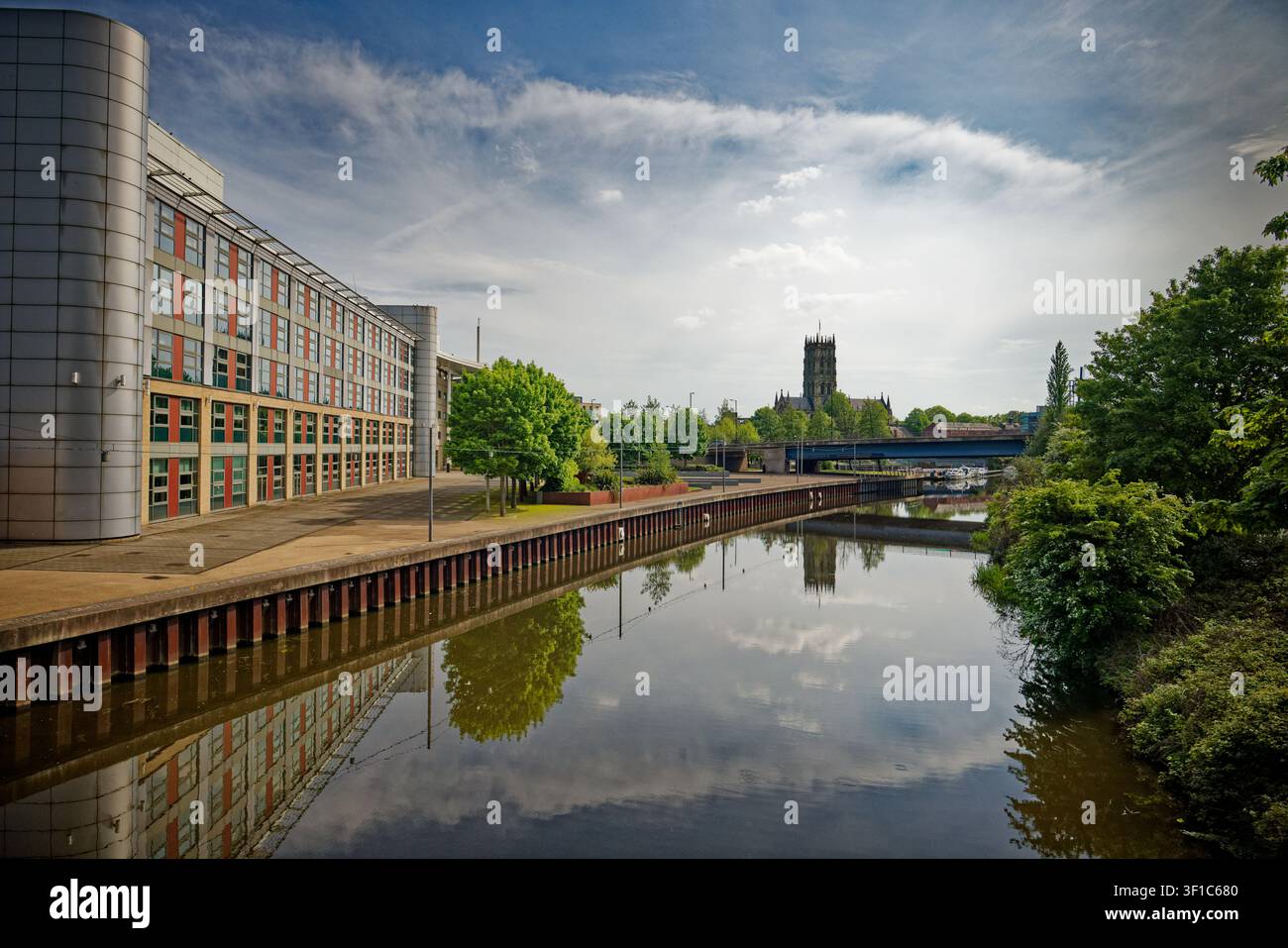 Der beeindruckende Turm einer großen Kirche spiegelt sich im stillen Wasser eines Kanals neben dem Campus des Doncaster College and University Centre wider. Stockfoto