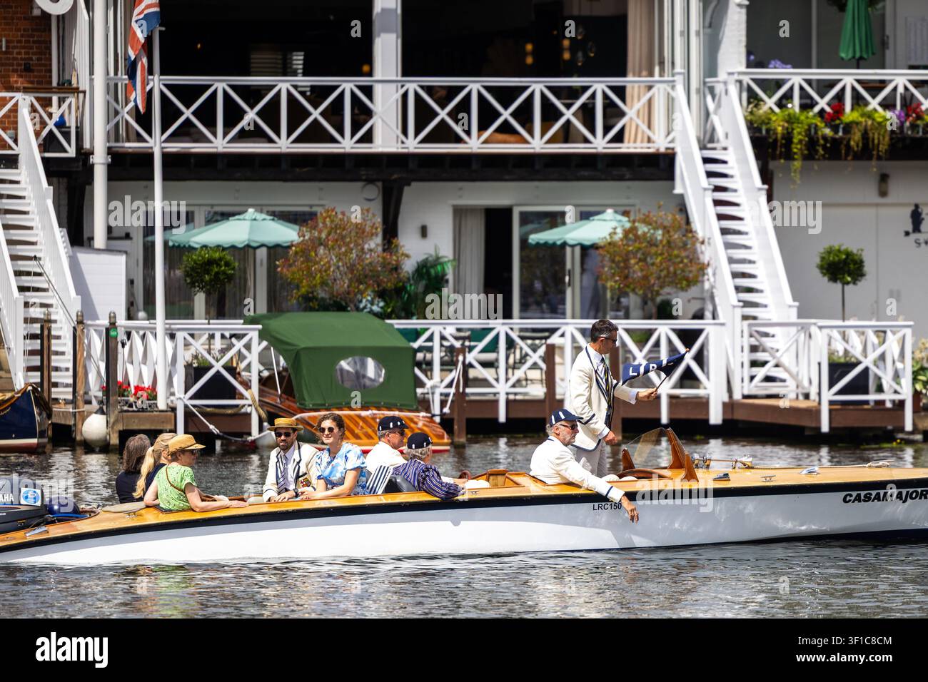 Stylisch gekleidete Menschen gleiten auf einem klassischen Holzschiff entlang der Themse während der Henley Regatta Stockfoto