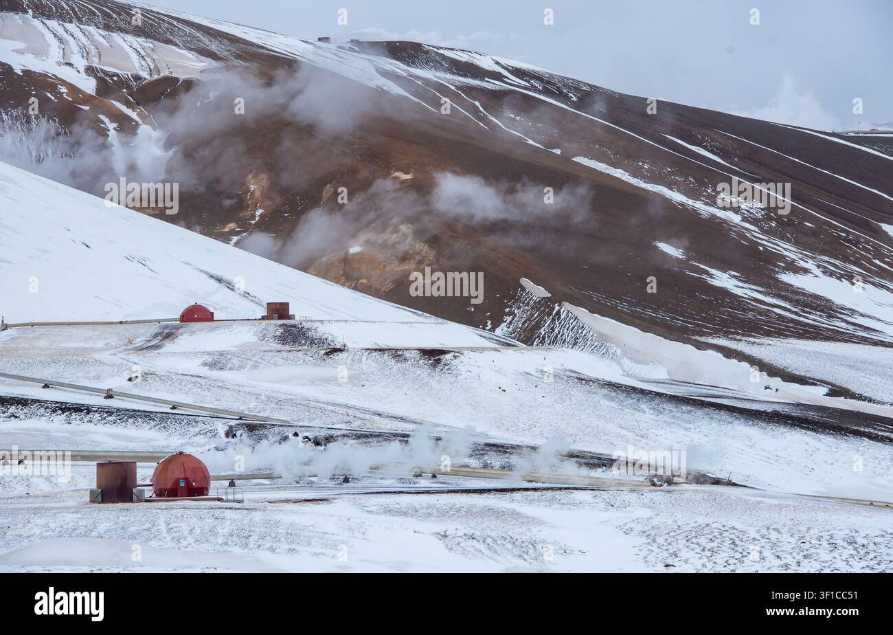Komponenten eines Geothermiekraftwerks mit markanten roten Kuppeln, Dampfwolken, die aus dem aktiven vulkanischen Krafla-Gebiet in Island aufsteigen Stockfoto