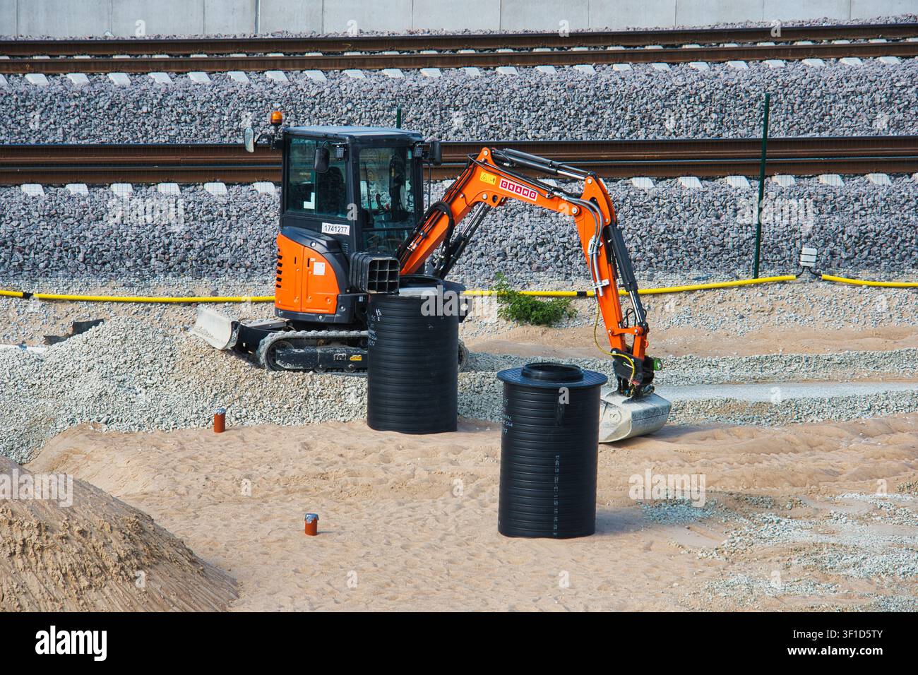 Kompakte orangefarbene Bagger auf einer Bahninfrastruktur-Baustelle Stockfoto