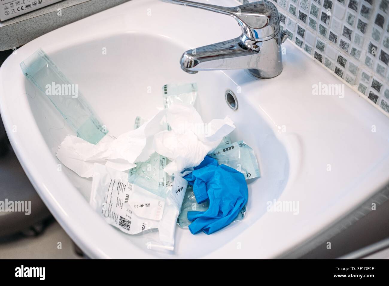Gebrauchter Dentalklinikabfall und Verpackungsfolien für sterile Instrumente liegen nach dem Eingriff weggeworfen. Dentalklinikabfall, Verpackungen für sterile Instrumente Stockfoto