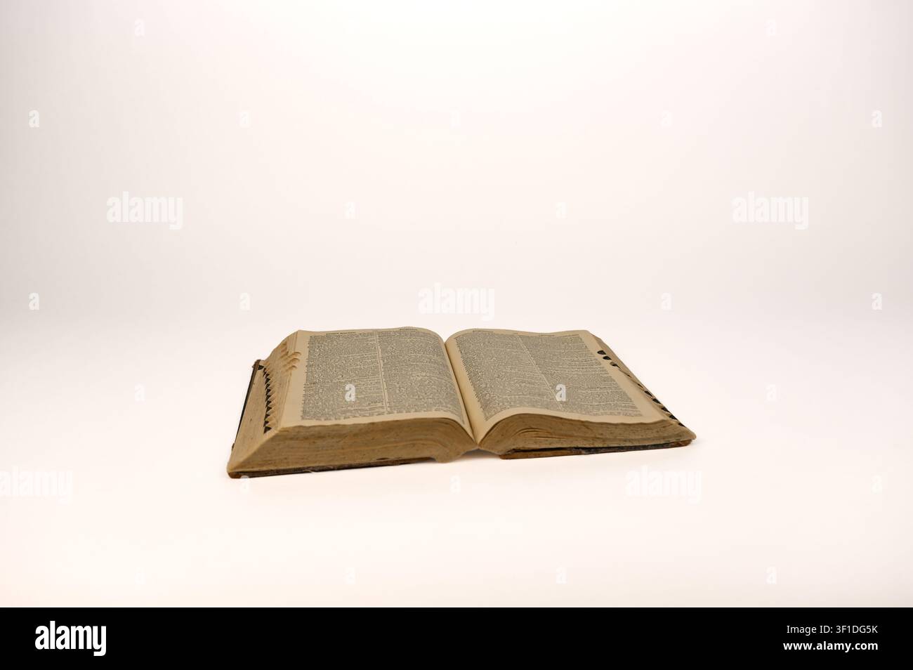 Hardcover-Wörterbuch aus den 1920er Jahren, aufgeschlagen mit gealterten Seiten auf weißem Hintergrund Stockfoto