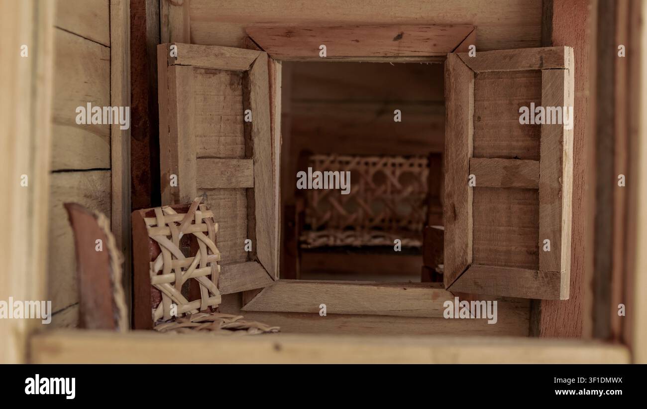 Miniatur Rustikales Holzhaus-Interieur mit offenen Fensterläden und Korbstühlen Stockfoto