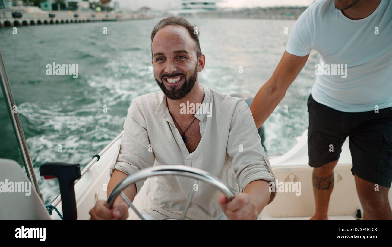 Bärtiger Mann am Steuerrad eines Bootes, der einen Sommerurlaub auf dem Wasser genießt Stockfoto