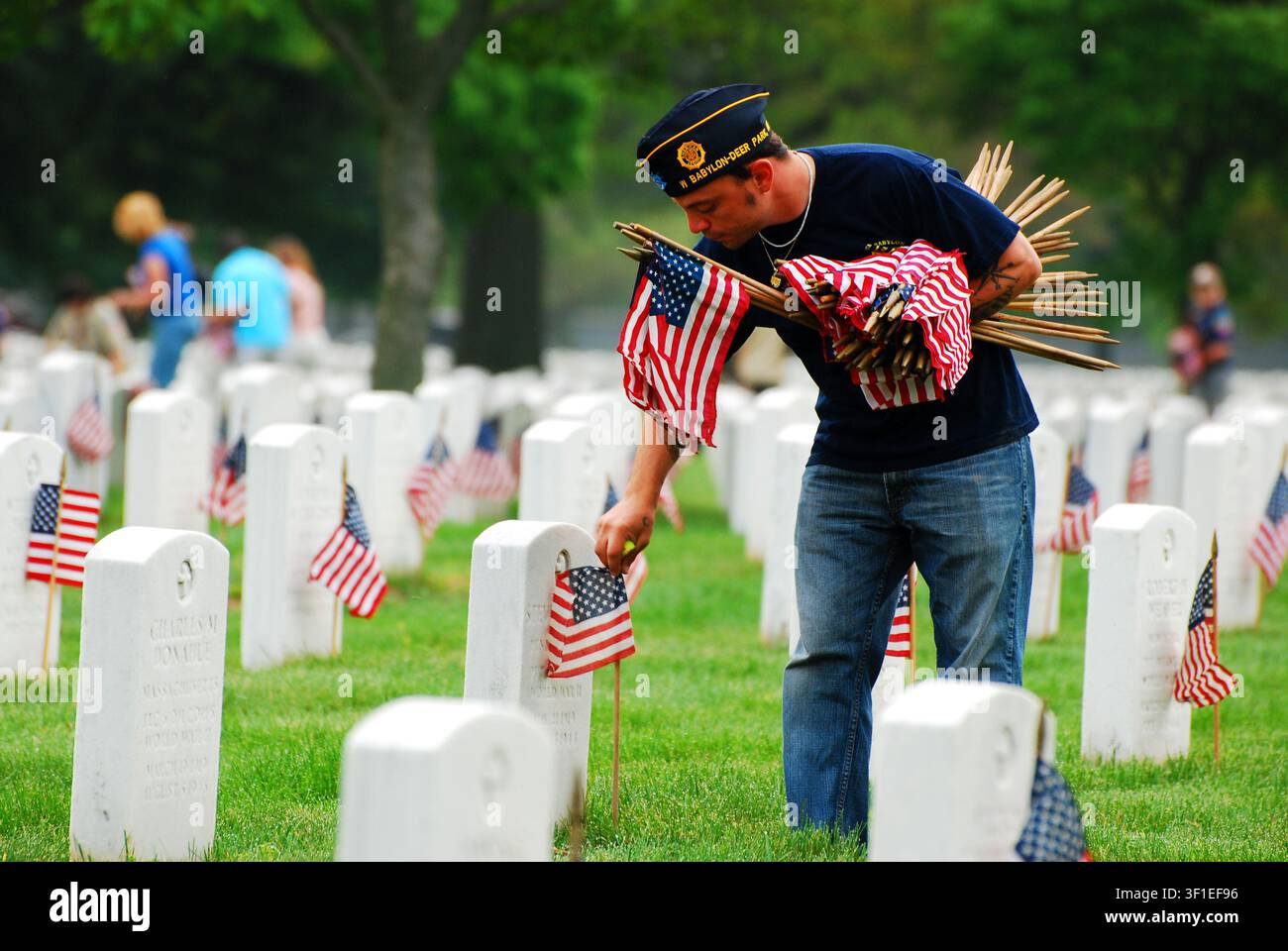 Freiwillige platzieren amerikanische Flaggen auf den Gräbern von Militärangehörigen und ihren Familien auf einem nationalen Militärfriedhof am Gedenktag Stockfoto