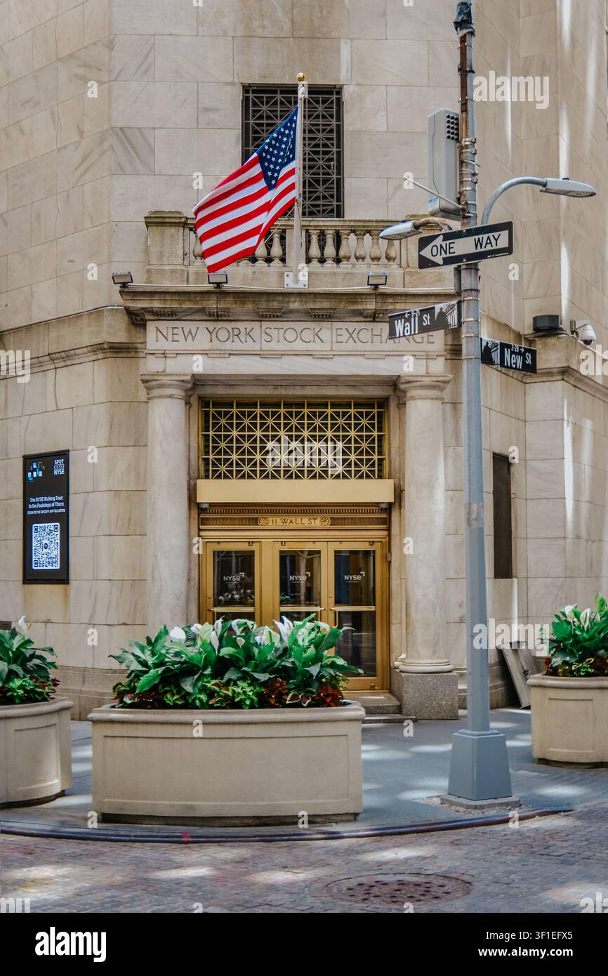 New York City, USA – 8. Juni 2026: Eingang der NYSE an der Wall und New Street mit einer amerikanischen Flagge, goldenen Türen und Straßenschildern. Stockfoto