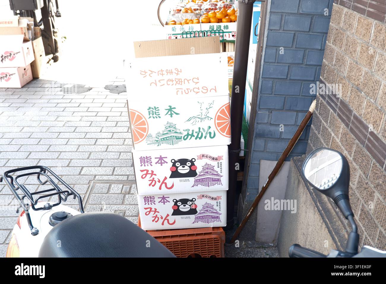 Gestapelte Pappkartons mit lokalen Mandarinen, die das Kumamon-Maskottchen auf einer Straße in Kumamoto, Japan, zeigen Stockfoto
