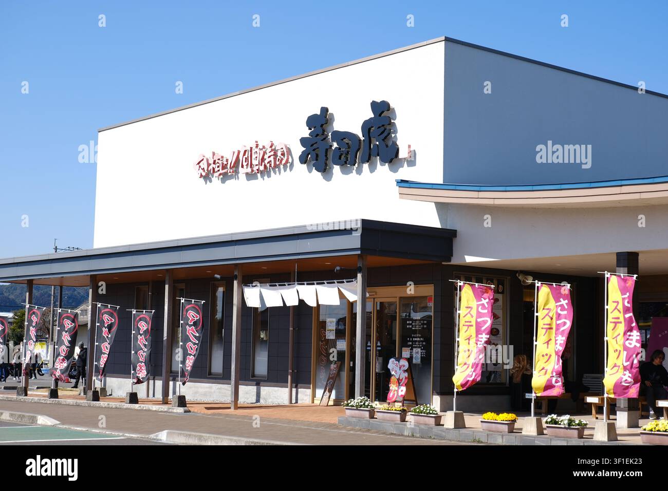 Die moderne Außenseite und Schaufensterfront eines lokalen Kaitenzushi-Restaurants (Förderband-Sushi) unter einem klaren blauen Himmel in der Stadt Kushima, Miyazaki, Japan Stockfoto