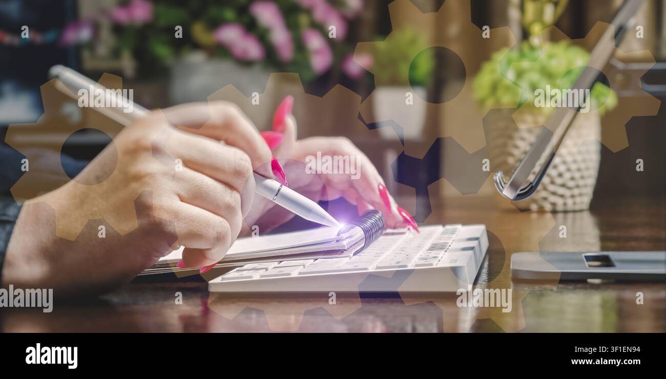 Systemintegration und Strategie. Geschäftsfrau arbeitet am Büroarbeitsplatz mit holografischem Zahnrad-Overlay, das Ingenieurwesen und Management symbolisiert. Stockfoto