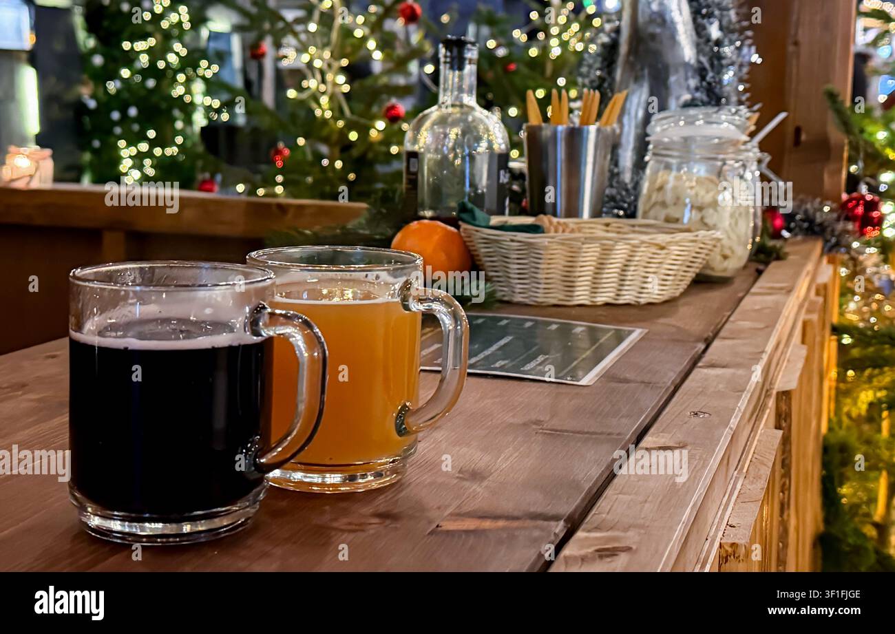 Zwei Glühweinpunsch auf einer hölzernen Thekenplatte, dekoriert mit Weihnachtslichtern und festlichen Elementen in einer gemütlichen Feiertagsstimmung Stockfoto