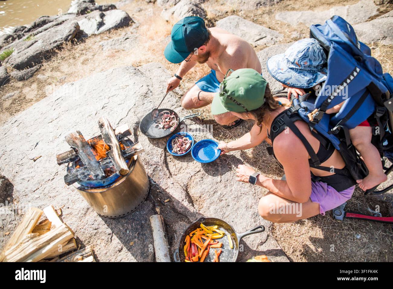 Ansicht von oben einer Familie, die draußen über einem Feuer das Abendessen kocht Stockfoto